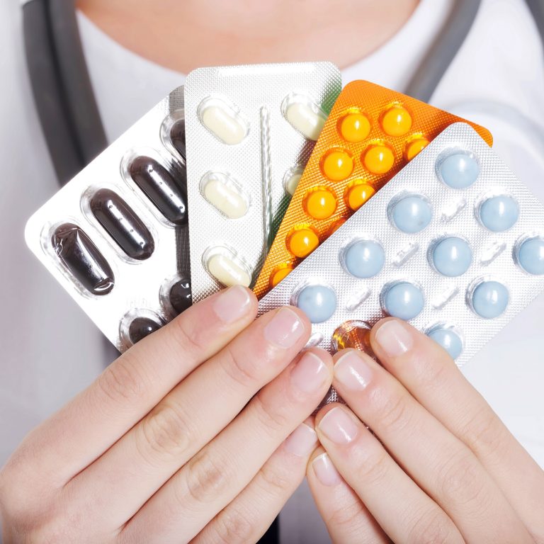 Young female doctor with pills. Isolated on white.