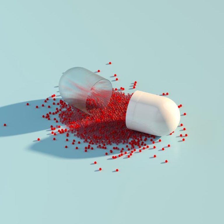 Digital generated image of abstract opened plastic capsule pill with small red spheres inside on pastel blue background.